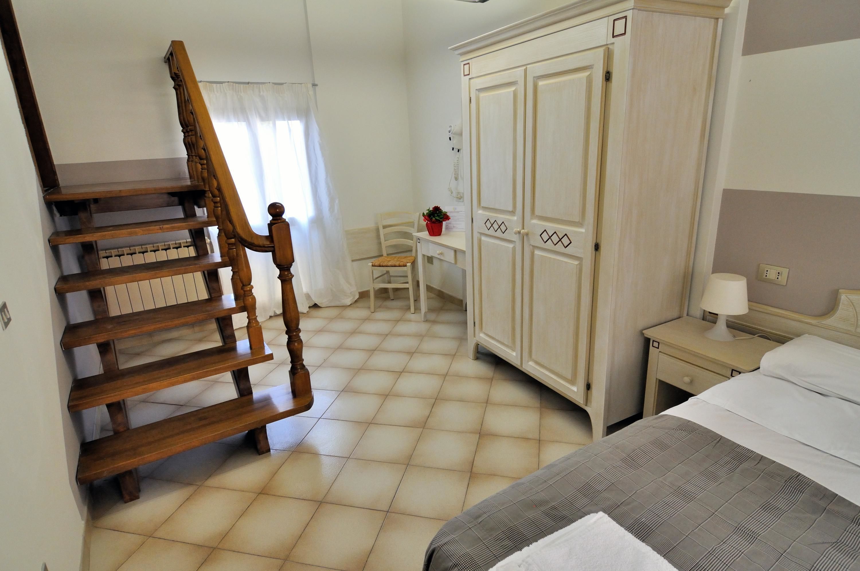 Quarto com escada de madeira, uma cama, guarda-roupa e uma escrivaninha com cadeira.