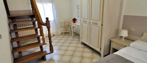 Quarto com escada de madeira, uma cama, guarda-roupa e uma escrivaninha com cadeira.