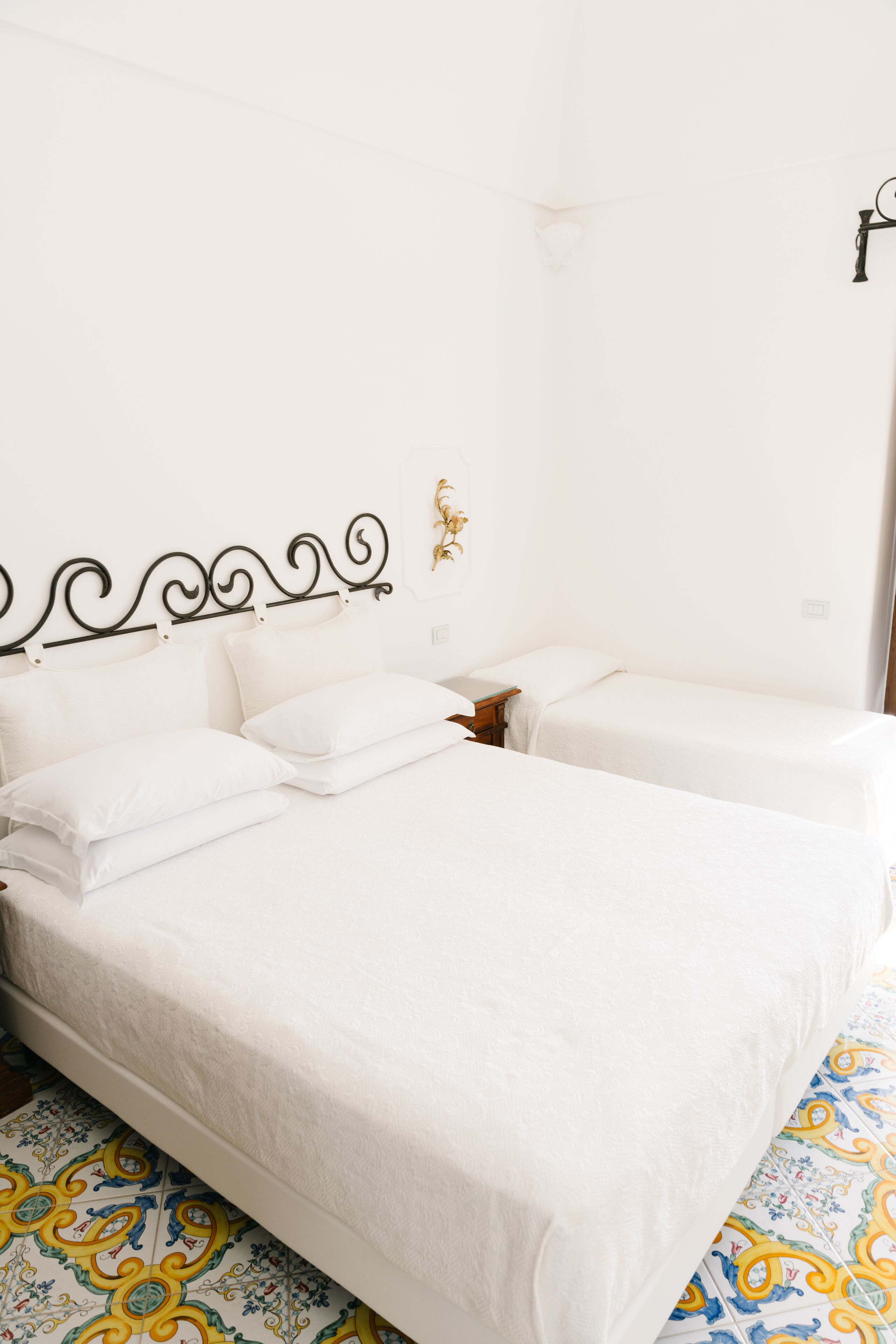 Ein Hotelzimmer mit einem großen Bett, einem kleineren Bett und einem Nachttisch.