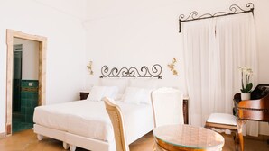 Une chambre à coucher avec un lit, deux chaises, une petite table et un rideau.