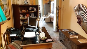 A home office with a desk, computer, printer, and bookshelf. There is a dining area with a table and chairs, and a living room with a sofa and a decorative fan. - Cavour il Conte Camillo Bed&Breakfast (Palermo)