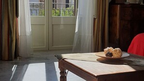 A room with a large window, a wooden table with a plate of pastries, and a mirror on the wall. - Cavour il Conte Camillo Bed&Breakfast (Palermo)