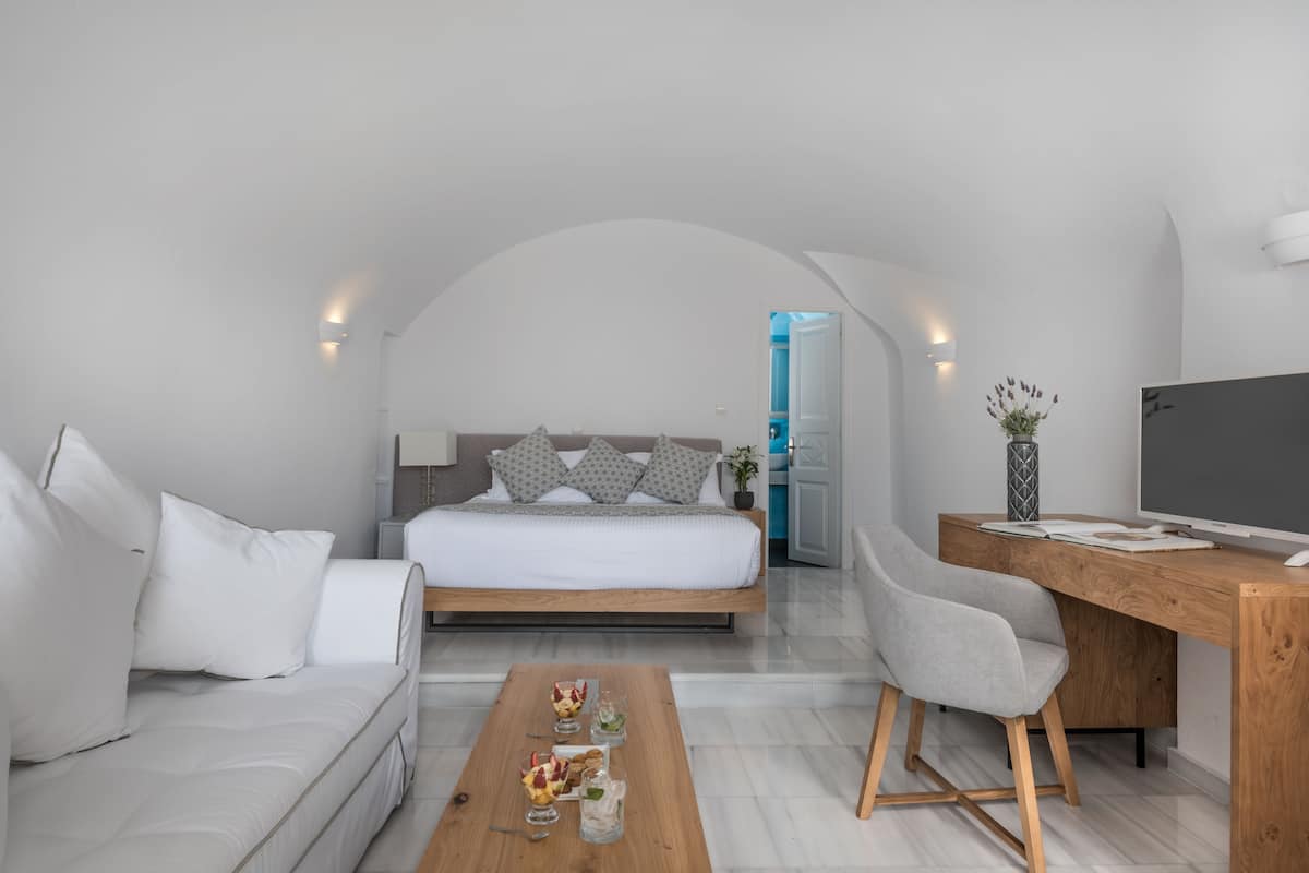 A modern bedroom with a bed, a desk, and a sofa.