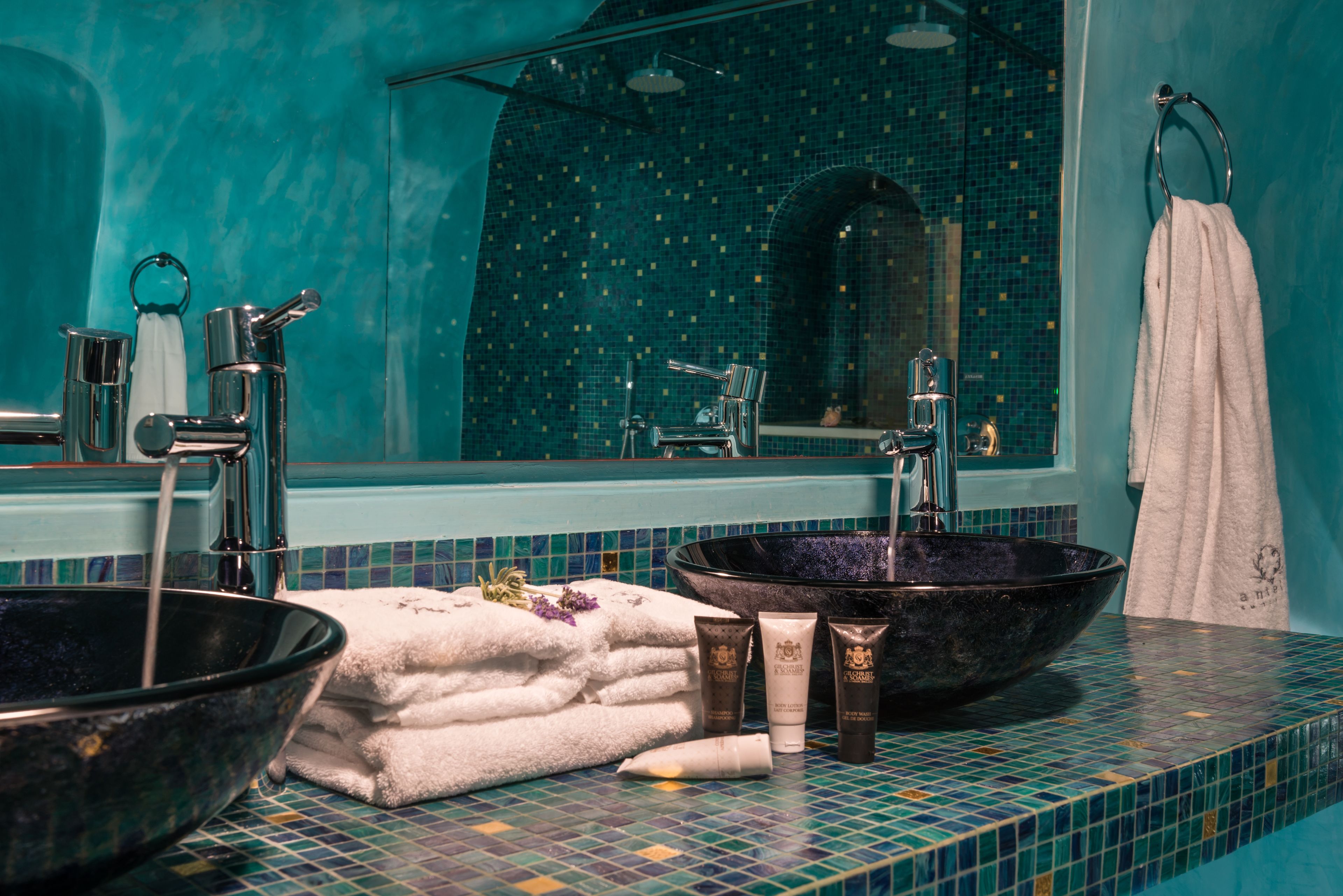 A bathroom with a large mirror, two sinks, and a towel rack.