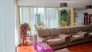A living room with a sofa, chairs, a plant, and a bookshelf. - Solar dos Marcos Rural Accommodation (Mogadouro)