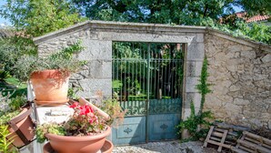 A stone building with a metal gate, surrounded by greenery and potted plants. - Solar dos Marcos Rural Accommodation (Mogadouro)