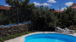 A clear blue swimming pool with a stone deck, surrounded by greenery and a stone wall. - Solar dos Marcos Rural Accommodation (Mogadouro)