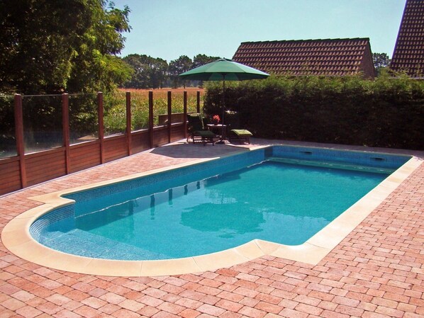 Piscina rectangular con borde de azulejos, rodeada por un patio de ladrillo.