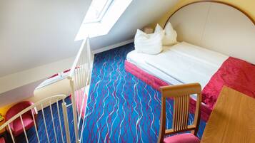 Une chambre avec un lit superposé, une fenêtre et un tapis à motifs.