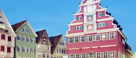 A historic building with a clock tower, surrounded by cobblestone streets and other colorful buildings.