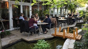 An outdoor cafe with tables and chairs, a small wooden bridge over a water feature, and potted plants. - Hotel am Schillerpark (Esslingen)