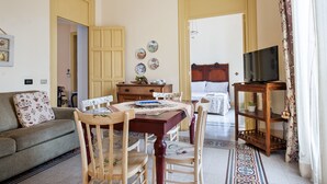 Un salon confortable avec un canapé, une table à manger, des chaises, un meuble pour la télévision et un lit avec une tête de lit.