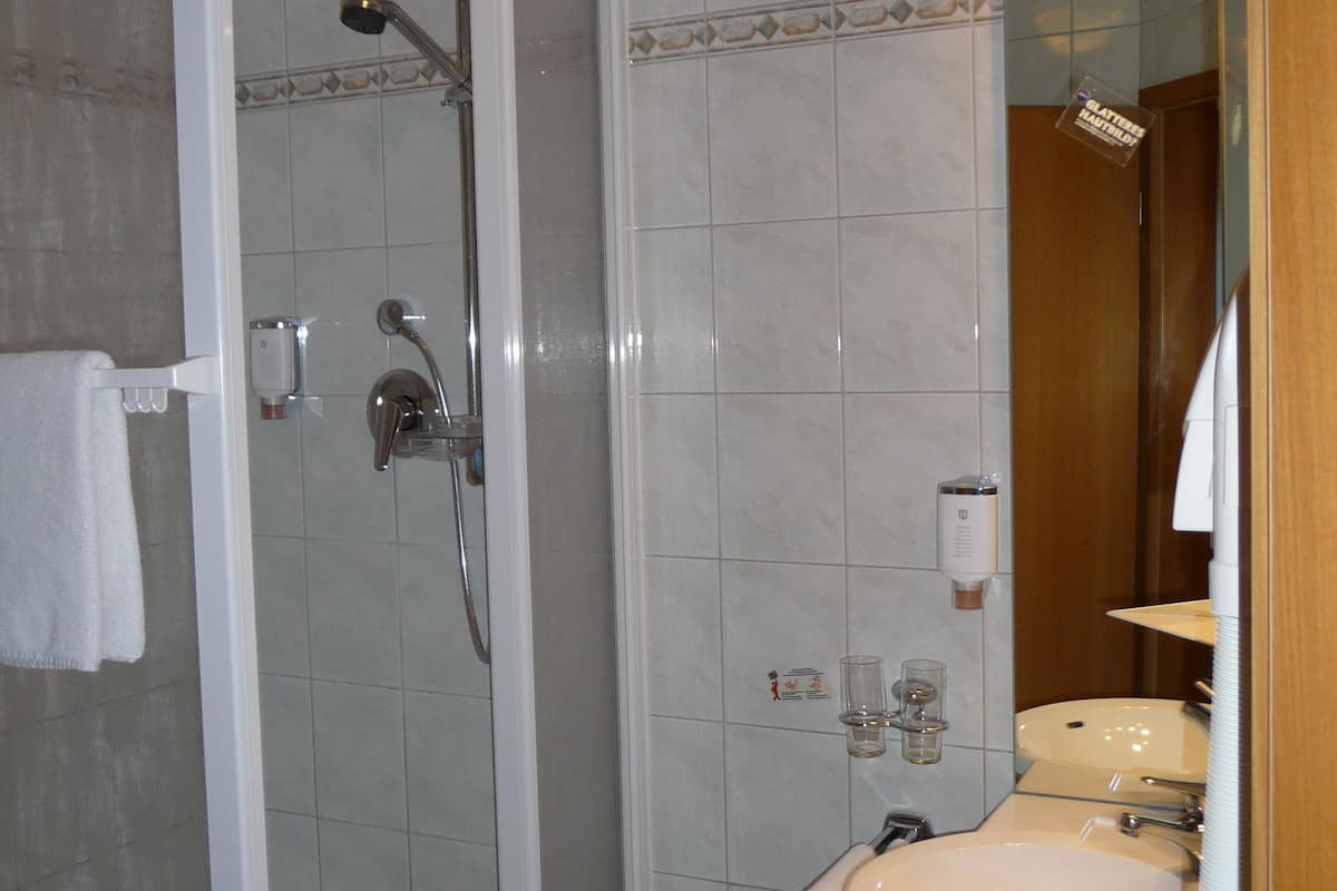 A bathroom with a glass-enclosed shower, a sink, and a mirror.
