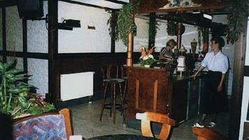 Ein Restaurantinneres mit Barbereich, Holzmöbeln und Topfpflanzen.