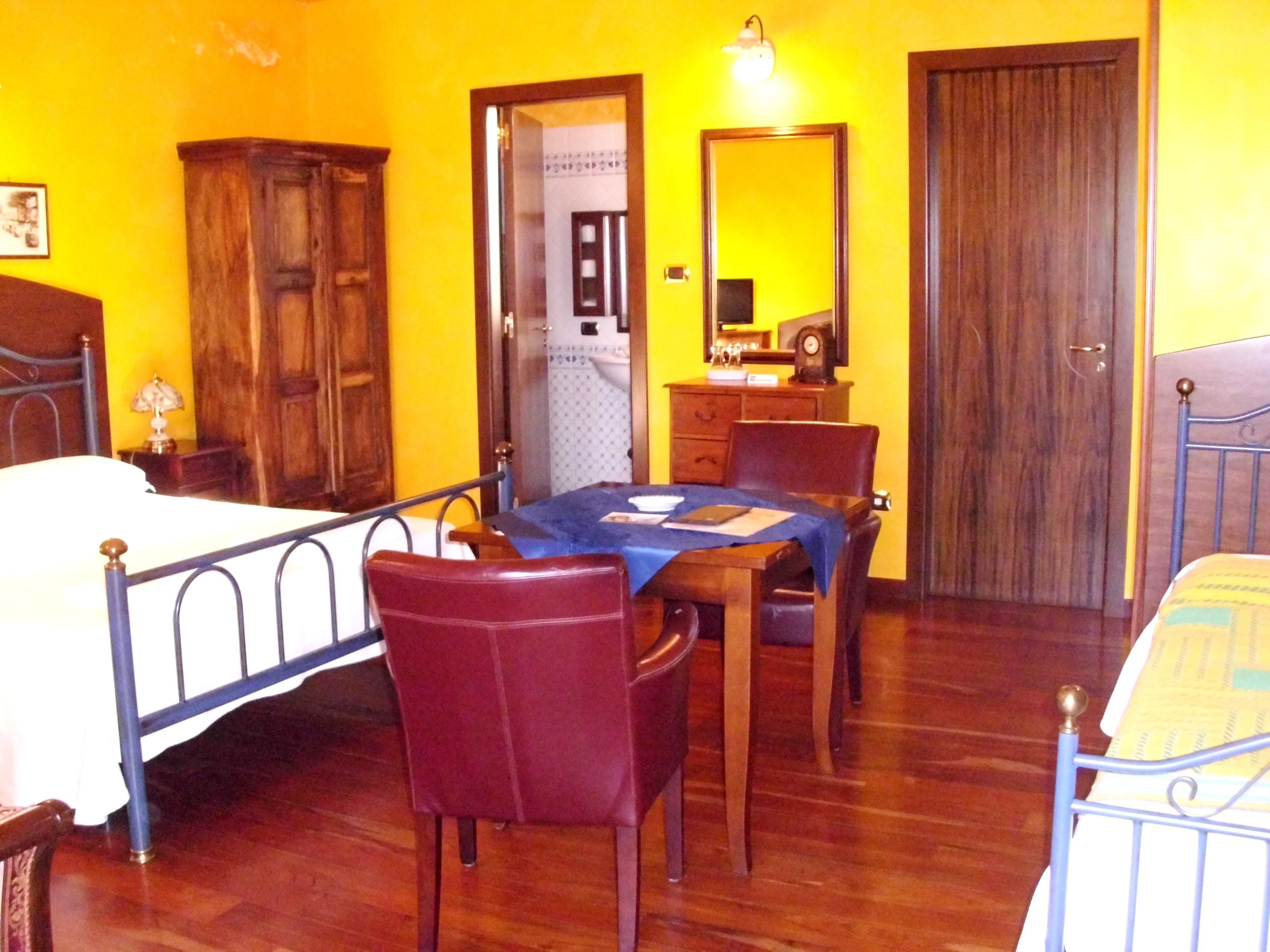 A room with a bed, a table with chairs, a dresser, and a mirror.