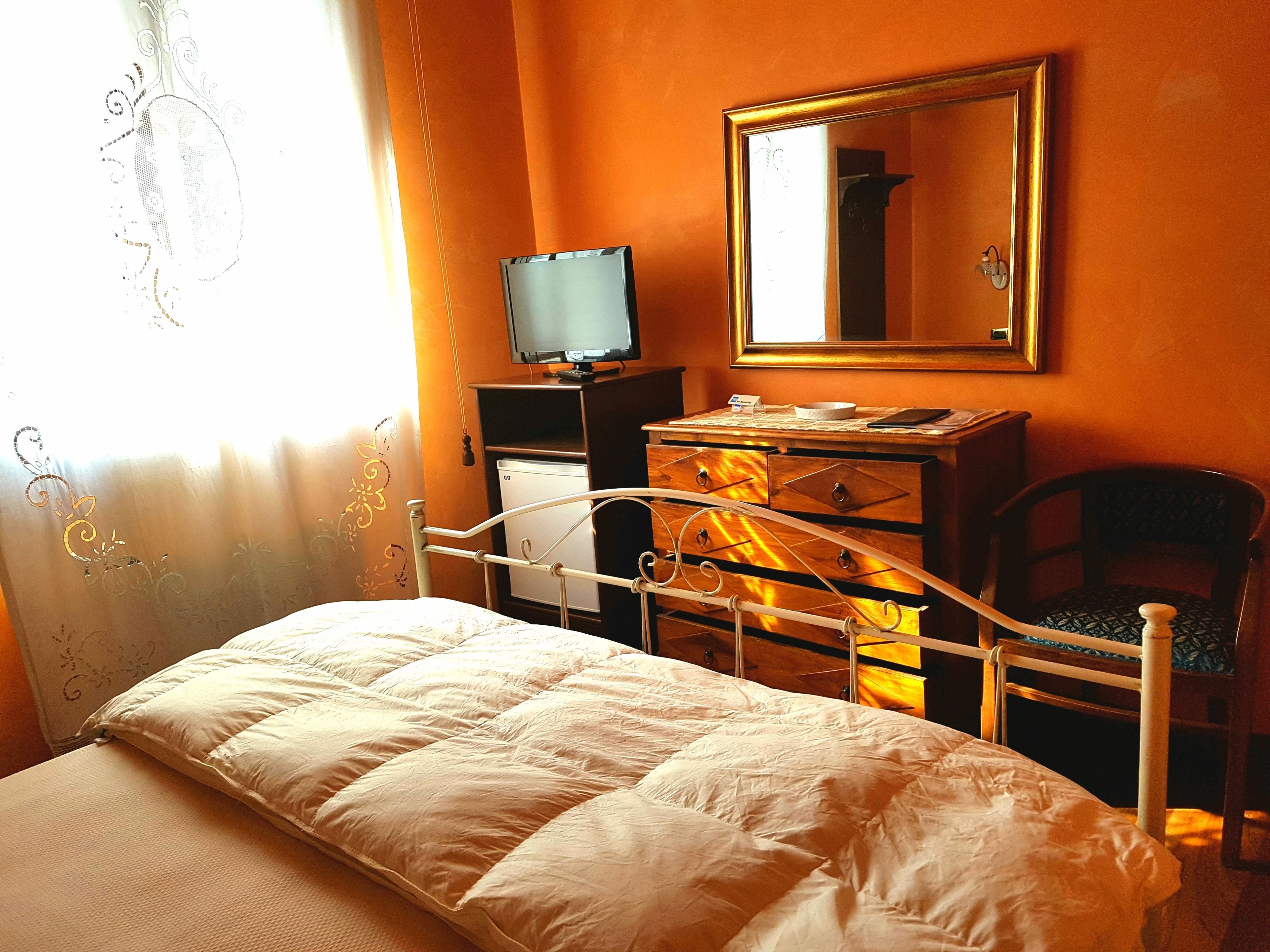 Une chambre à coucher avec un lit, une commode, une télévision et un fauteuil.
