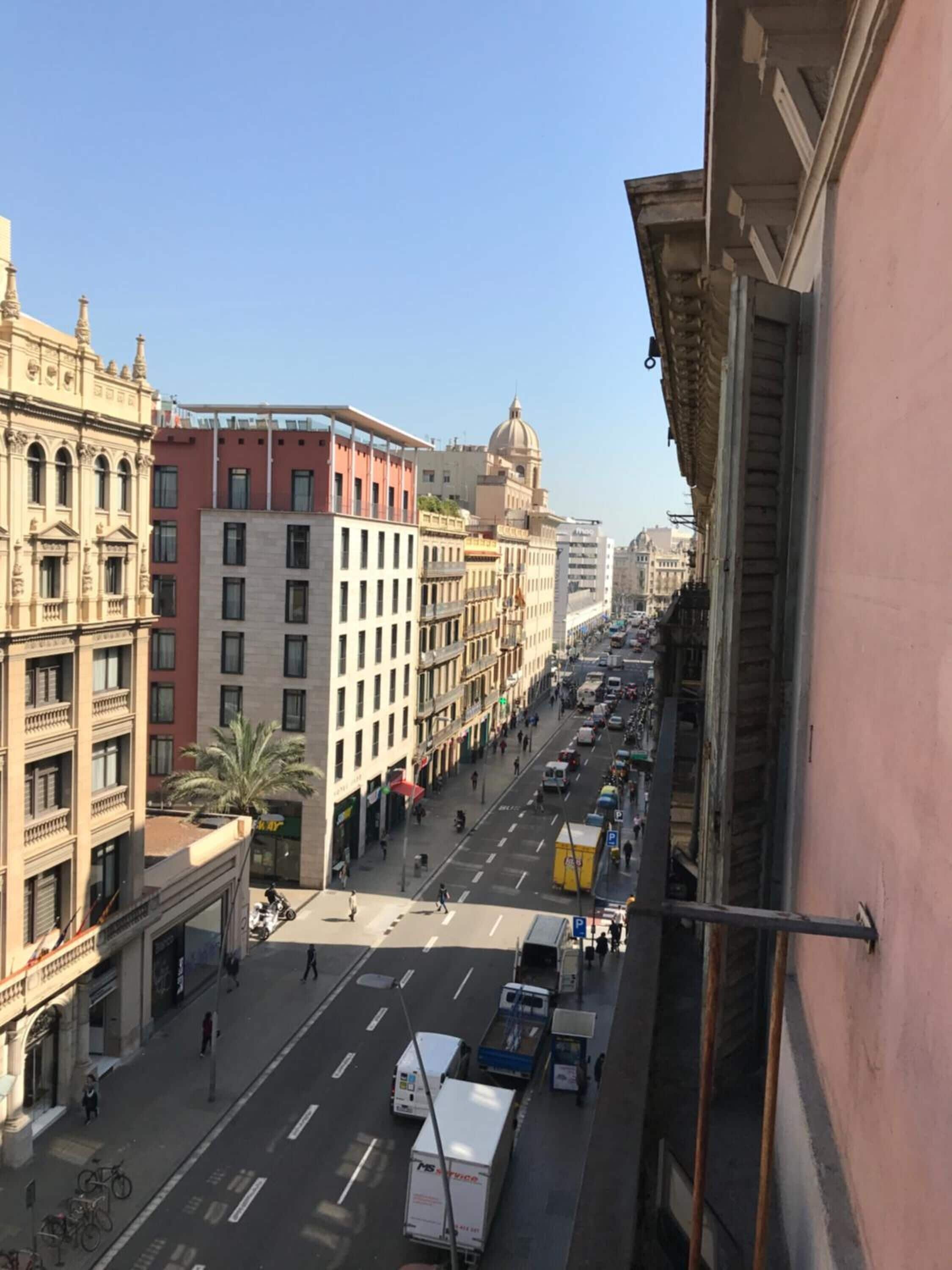 Vista de la calle con edificios, vehículos y peatones.