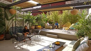 An outdoor patio area with seating, potted plants, and hanging baskets. - chic&basic Lemon Boutique Hotel (Barcelona)