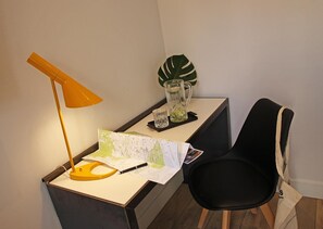 A desk with a map, a lamp, a pitcher, and a chair.