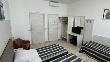 Ein Hotelzimmer mit Bett, Sessel, Fernseher und Kleiderschrank.