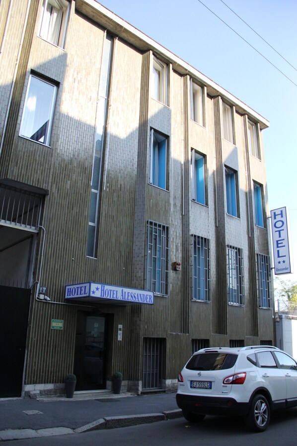 Un bâtiment d’hôtel avec une enseigne indiquant « HÔTEL ALESSANDER ».