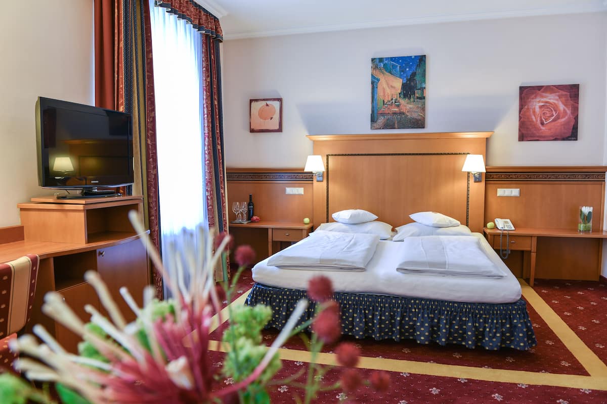 A hotel room with a bed, a TV, a desk, and a nightstand.