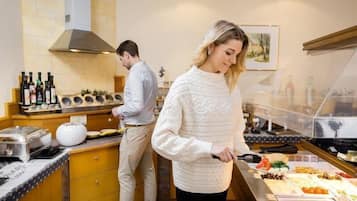 Zona de bufé con diversas opciones de comida, un hombre preparando alimentos y una mujer sirviendo.