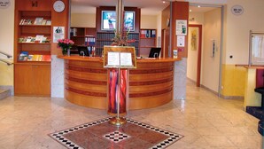 Un área de recepción con un mostrador de madera curvado, un reloj y un cartel de recepción.