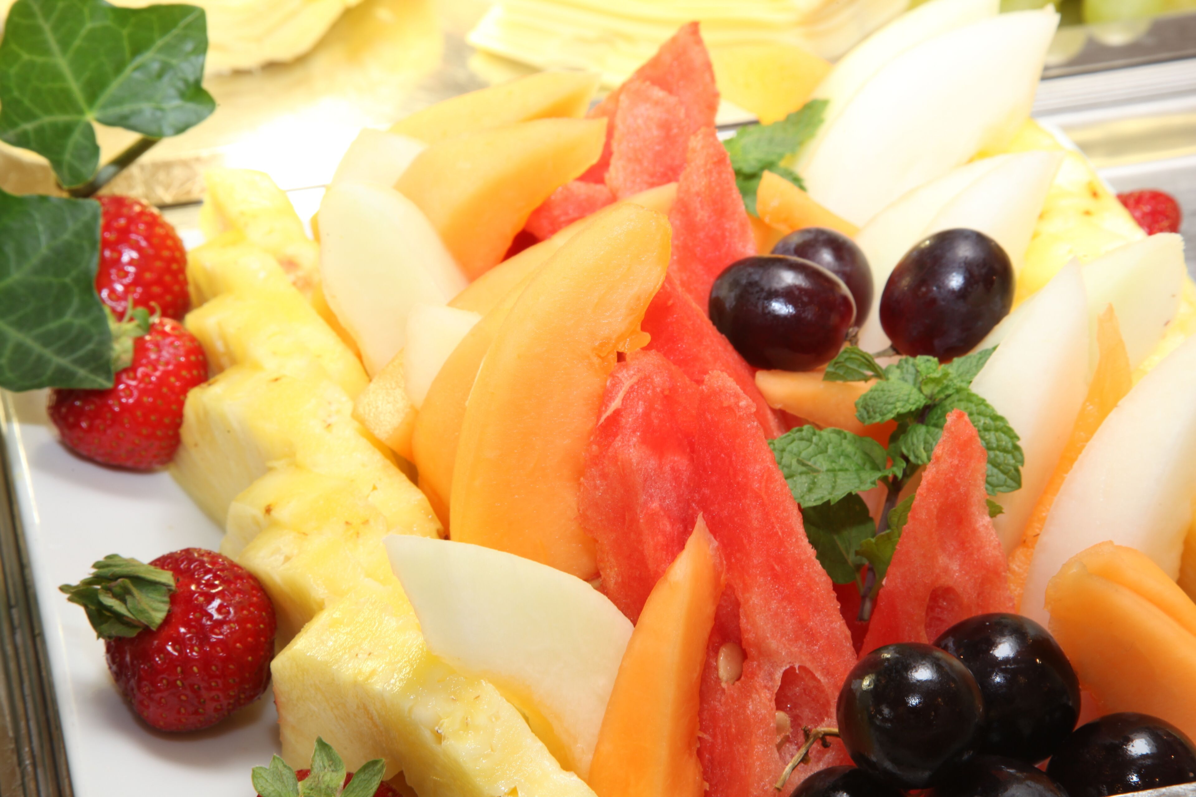 Eine Obstplatte mit Erdbeeren, Ananas, Wassermelone, Trauben und Minzblättern.