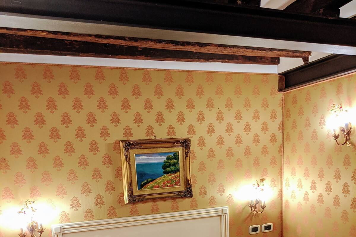 A hotel room with two beds, a painting on the wall, and two bedside lamps.
