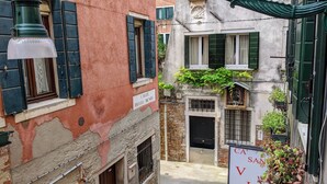 Une rue étroite bordée d’immeubles à l’architecture traditionnelle, avec notamment une enseigne indiquant « Calle Delle Mende » et une autre indiquant « Casa San Vio ».