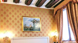 Une chambre d’hôtel avec un lit, un tableau au mur et une fenêtre avec des rideaux.