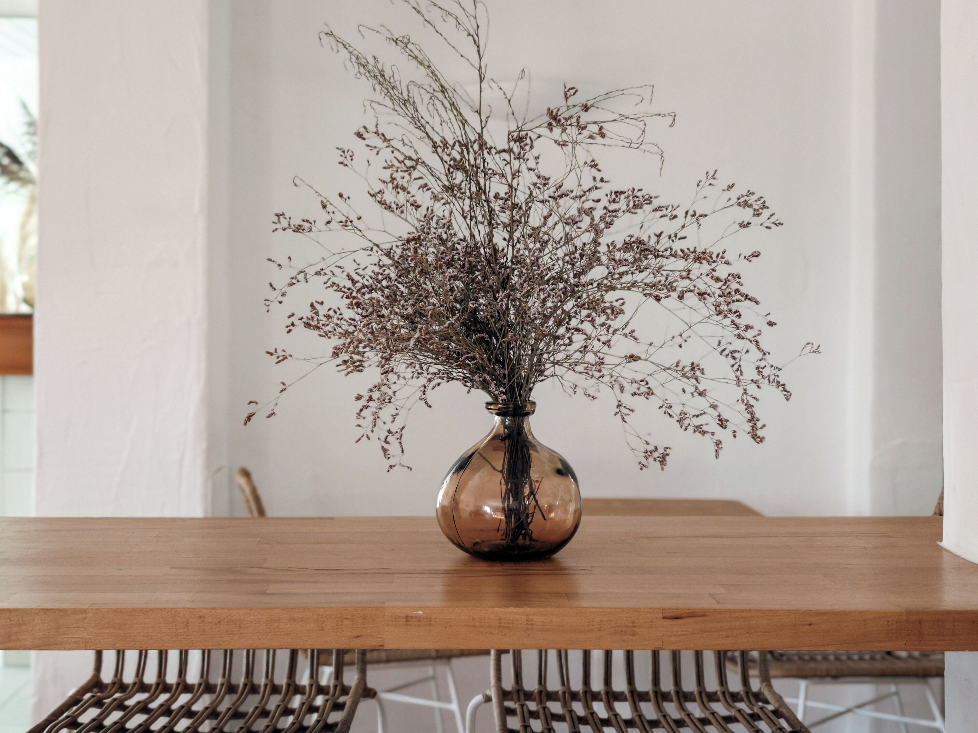 A clear view of a wooden table with a vase containing dried flowers.