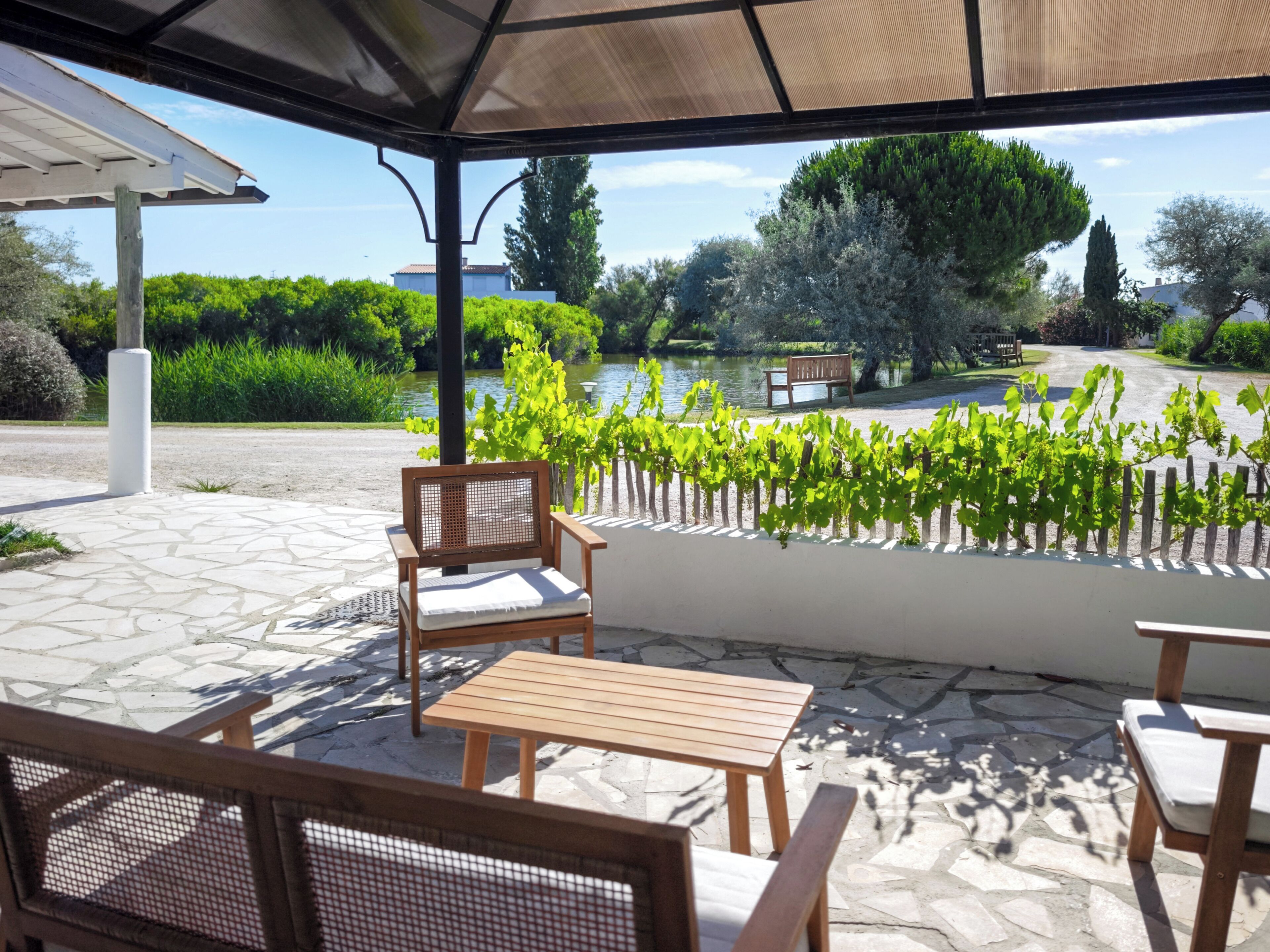 A covered outdoor seating area with a view of a lake and greenery.