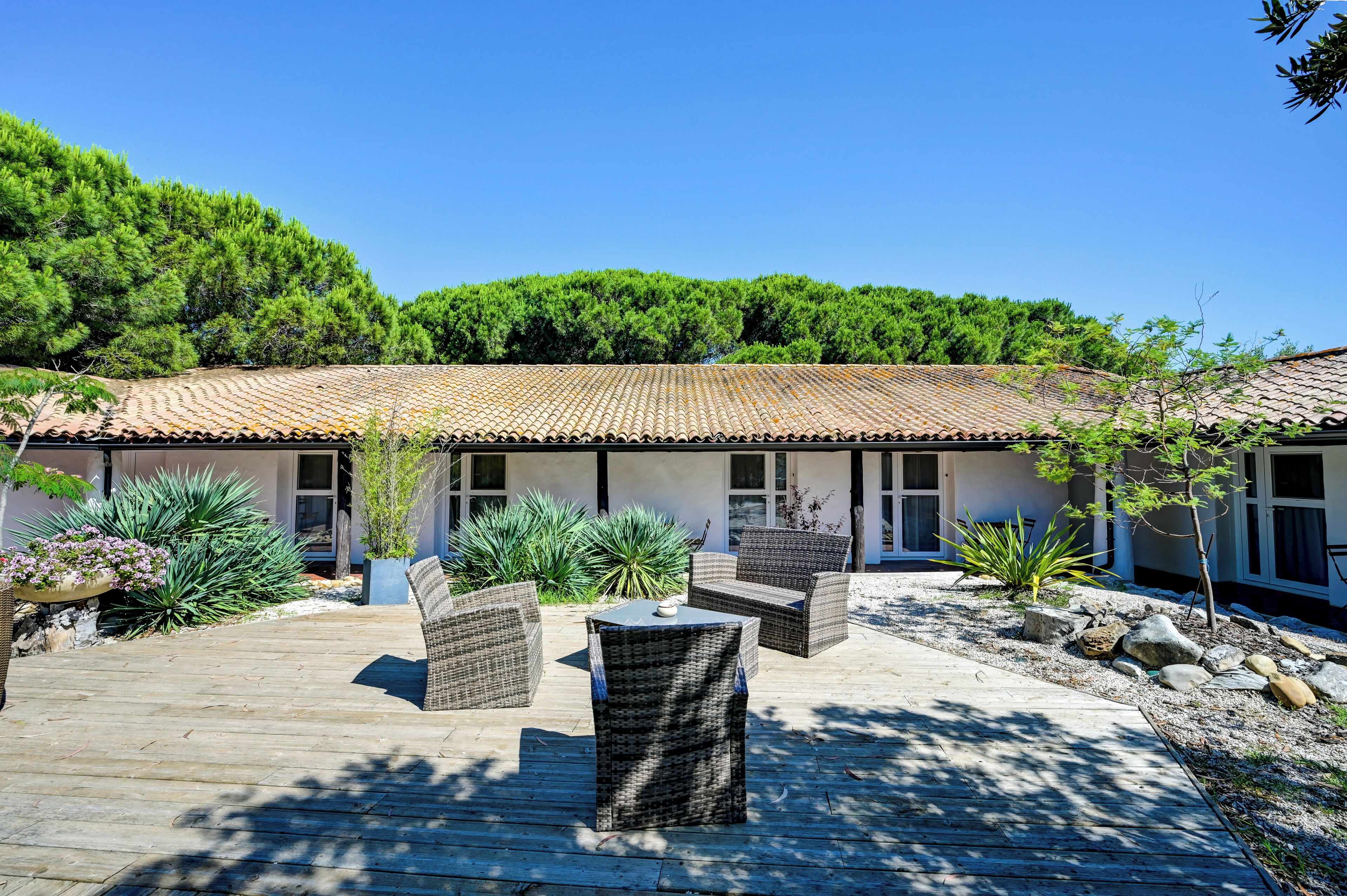 A building with a tiled roof, outdoor wicker furniture, and a wooden deck.