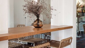 A wooden table with a vase of dried flowers, wicker chairs, and a white wall in the background. - Hôtel les Rizières (Saintes-Maries-de-la-Mer)