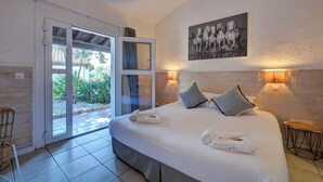 A bedroom with a large bed, a sliding glass door to a balcony, a framed picture on the wall, and two bedside lamps. - Hôtel les Rizières (Saintes-Maries-de-la-Mer)