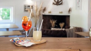 A wooden table with two drinks, a fireplace, and a wall-mounted anchor decoration in a living room. - Hôtel les Rizières (Saintes-Maries-de-la-Mer)
