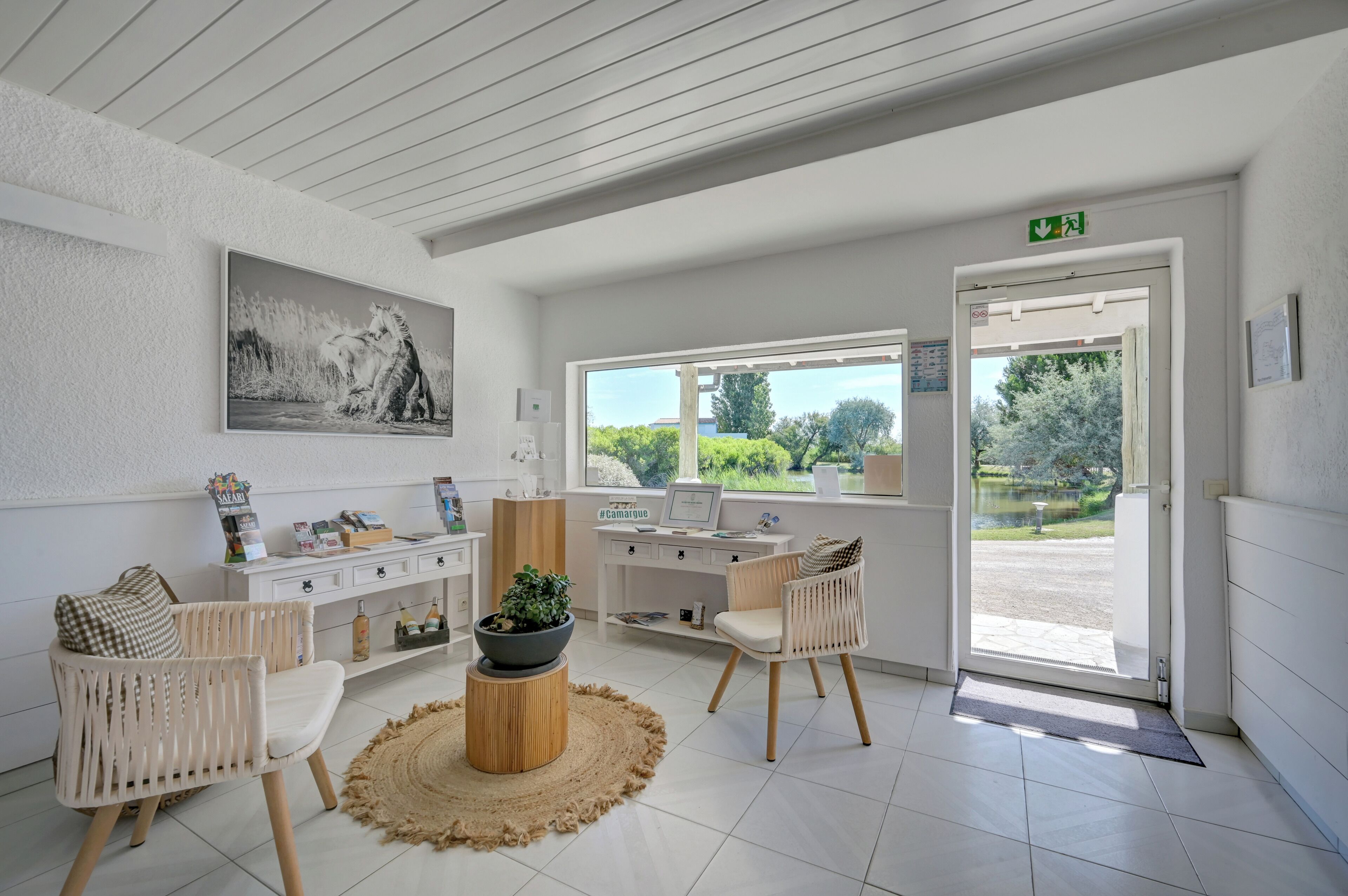 Une pièce moderne équipée d’un bureau, de chaises, d’une grande fenêtre et d’une porte donnant sur l’extérieur.