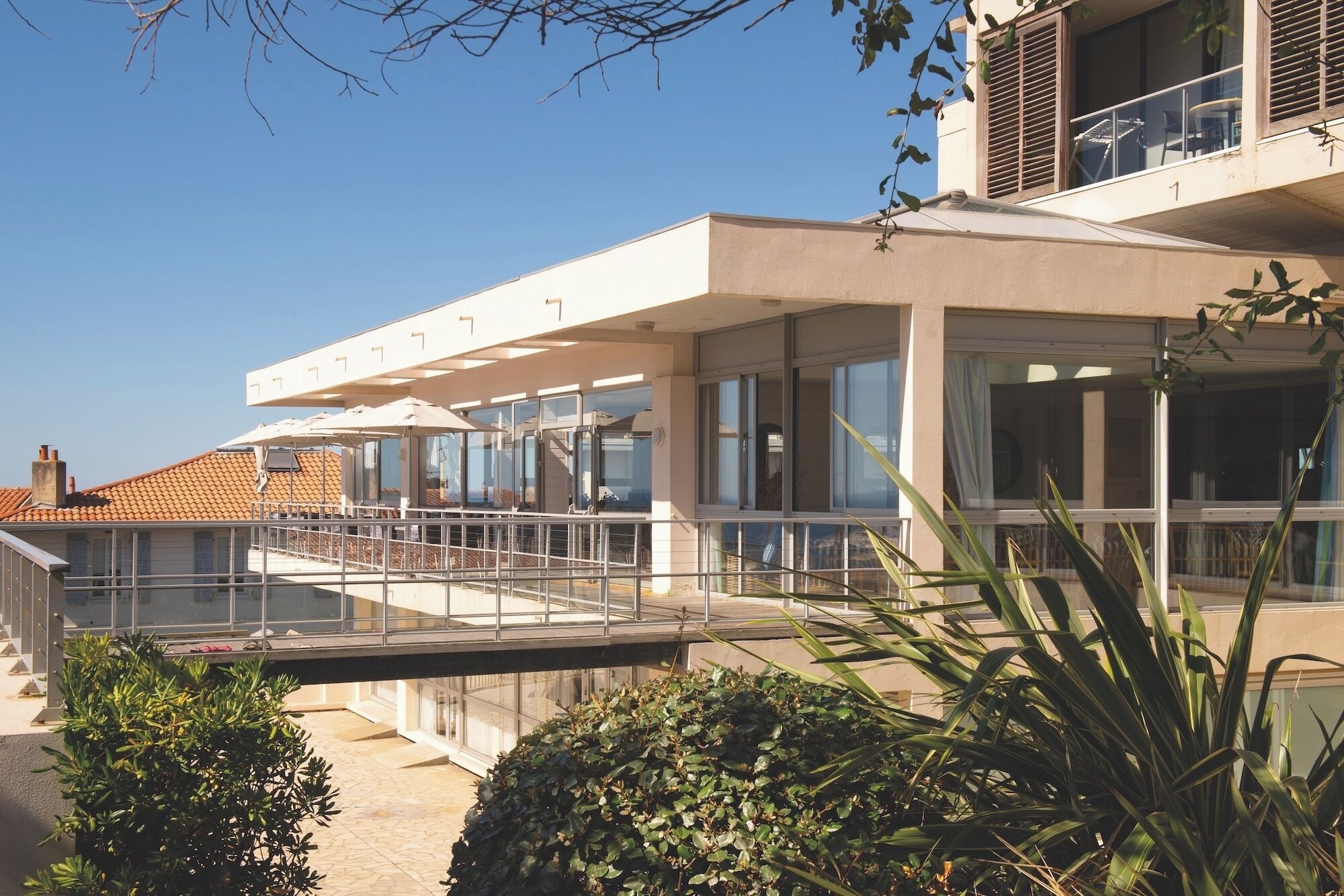 A modern building with a covered outdoor area, large windows, and a balcony.