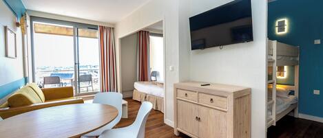 Una habitación moderna con una mesa de comedor, sillas, un sofá, un televisor y una cama.