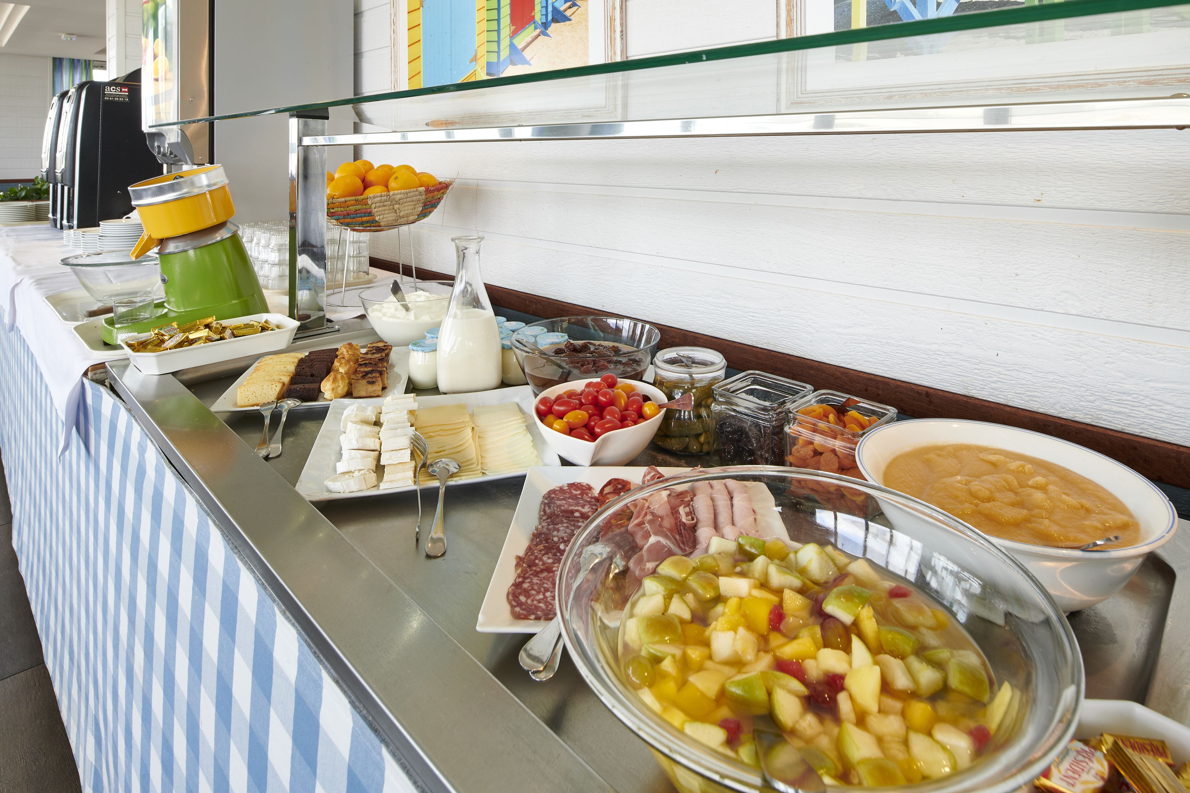 A buffet with various food items including fruits, cheeses, meats, and a bowl of soup.