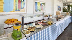 Un buffet proposant une variété de plats, un bar à jus et des œuvres d’art encadrées accrochées au mur.