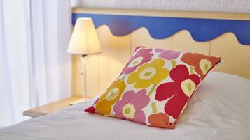 A bed with a colorful floral pillow, a bedside lamp, and a wavy headboard.