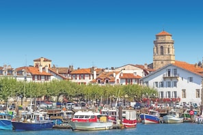 Un puerto con barcos, una torre y edificios con tejados rojos.