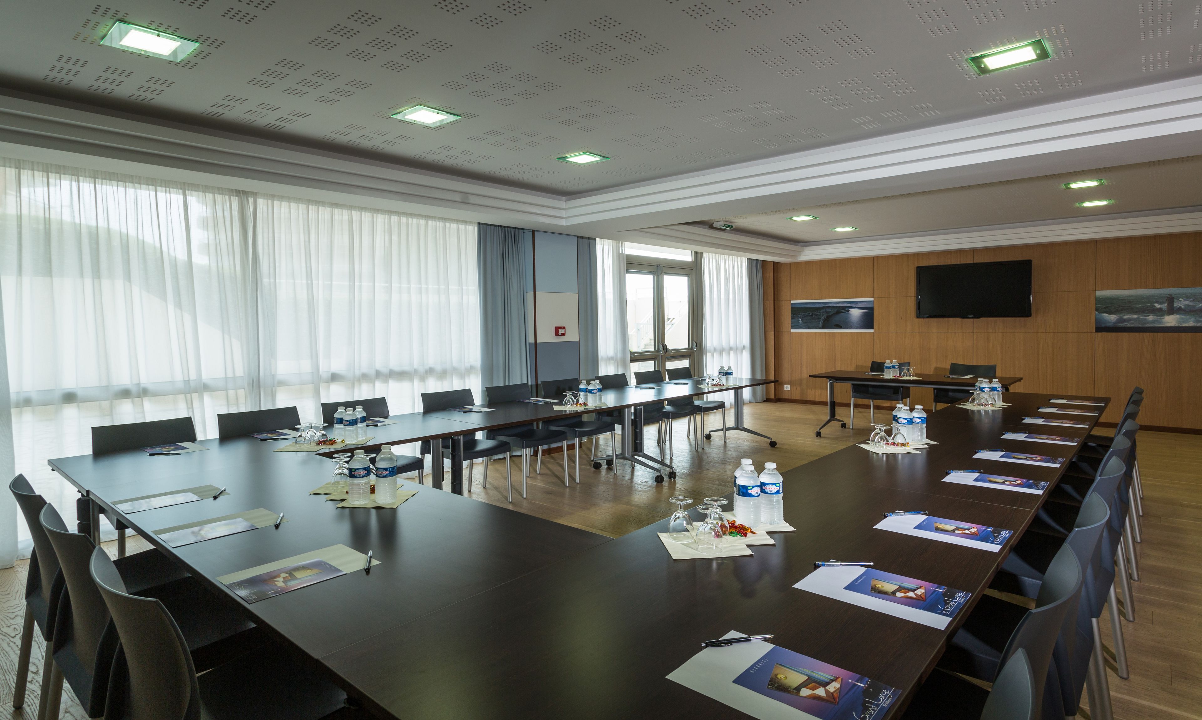 A conference room with a long table, chairs, water bottles, and papers.
