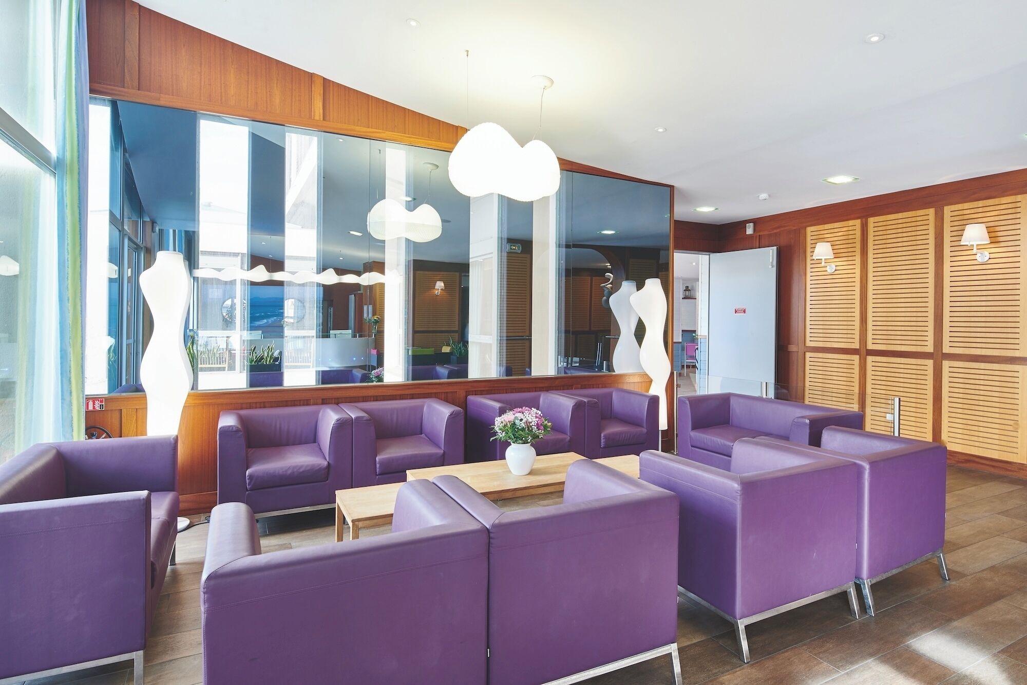 A modern lobby with purple seating, large windows, and a reflective wall.