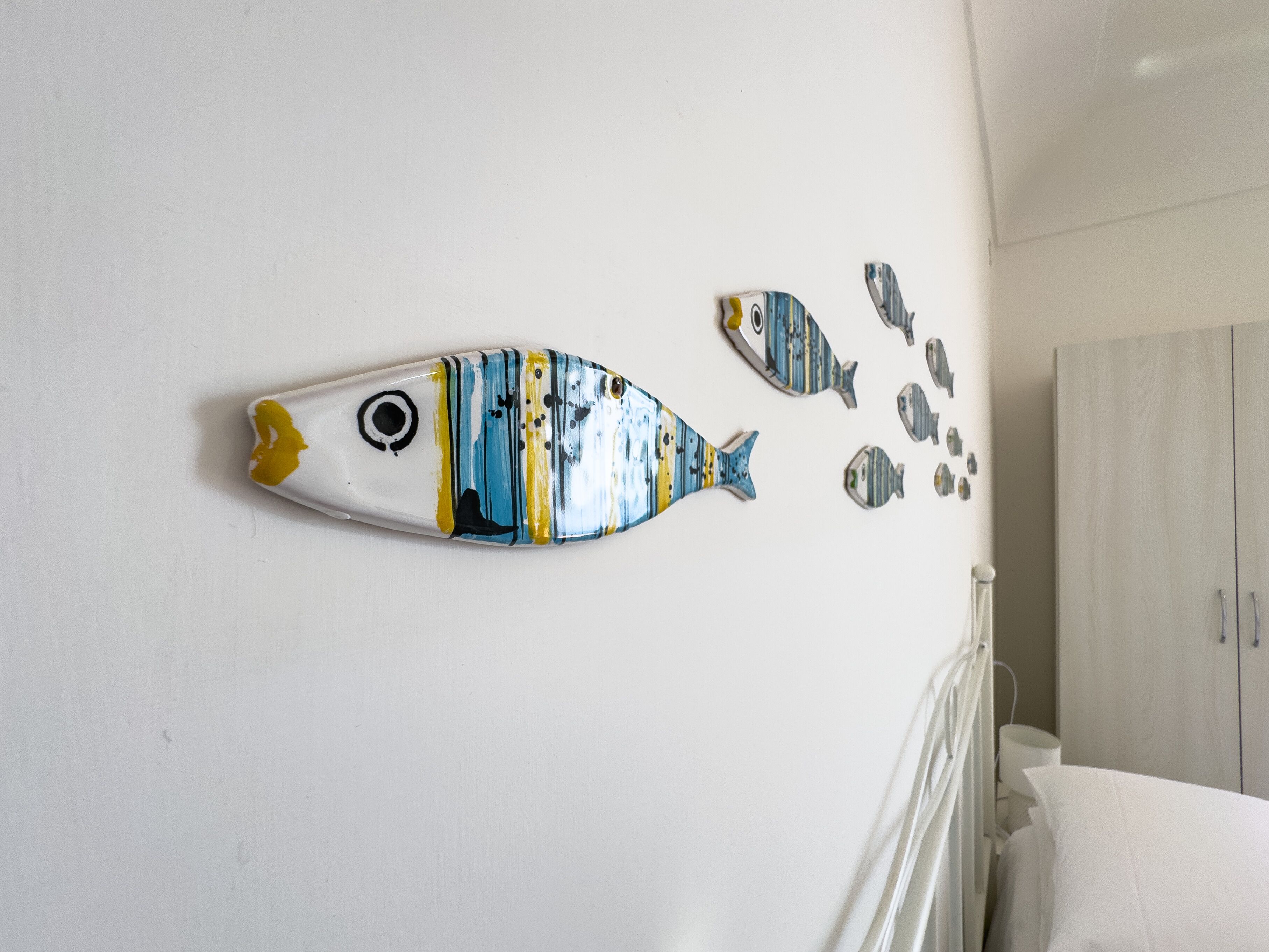 A wall with a large fish decoration and smaller fish pieces.