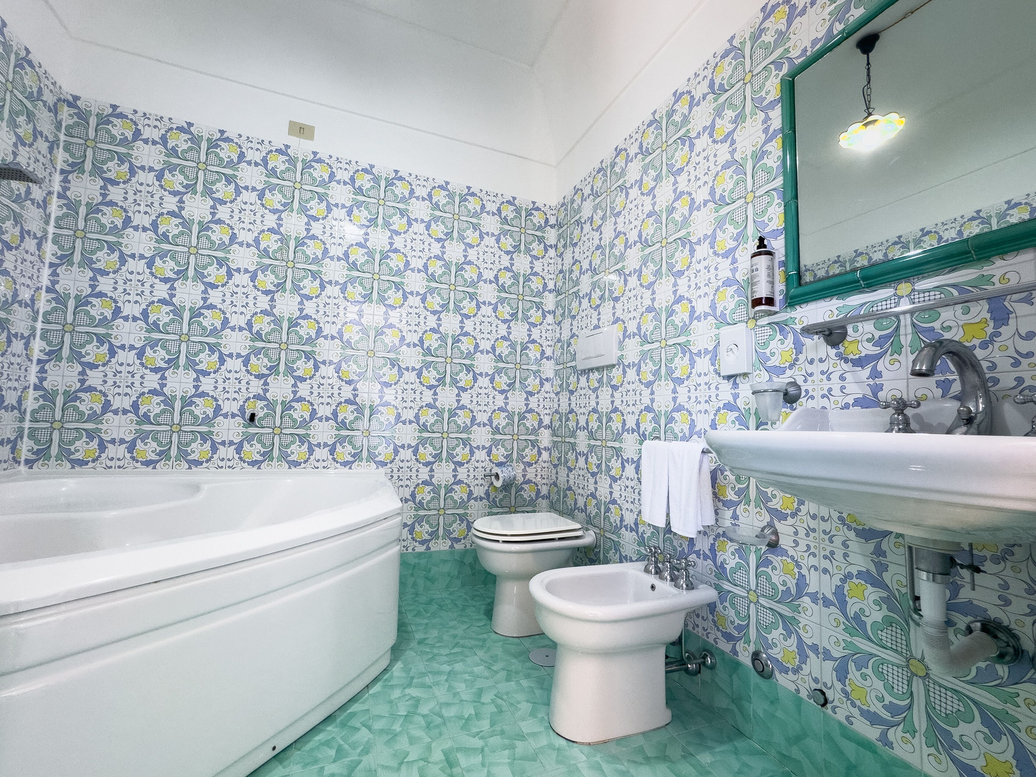 Ein Badezimmer mit Badewanne, Toilette, Bidet, Waschbecken und Spiegel.
