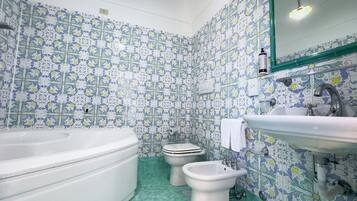 Ein Badezimmer mit Badewanne, Toilette, Bidet, Waschbecken und Spiegel.